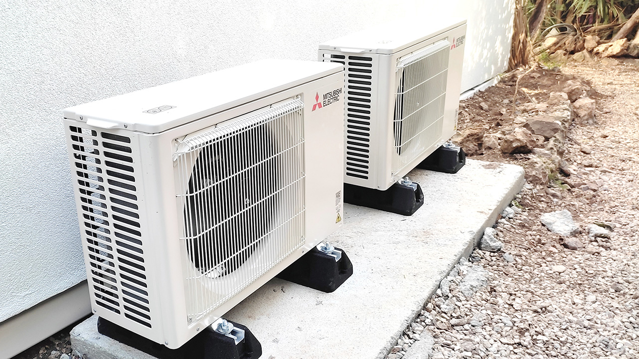 Deux groupes extérieurs de climatisation Mitsubishi Electric posés sur dalle et plots antivibratiles le long d'un mur — MSC Climatisation, Var