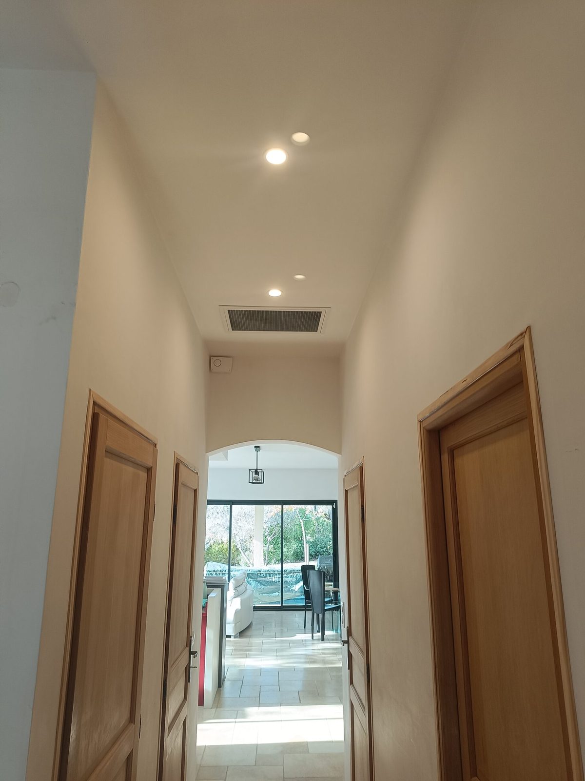 Couloir d'une maison avec une grille de climatisation gainable intégrée au plafond, seule partie visible d'une installation gainable terminée — MSC Climatisation dans le Var