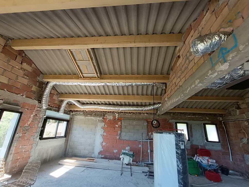 Réseau de gaines calorifugées d'une climatisation gainable tiré le long des pannes de la charpente avant la fermeture des plafonds, chauffe-eau emballé en attente de pose, chantier de rénovation dans le Var — MSC Climatisation
