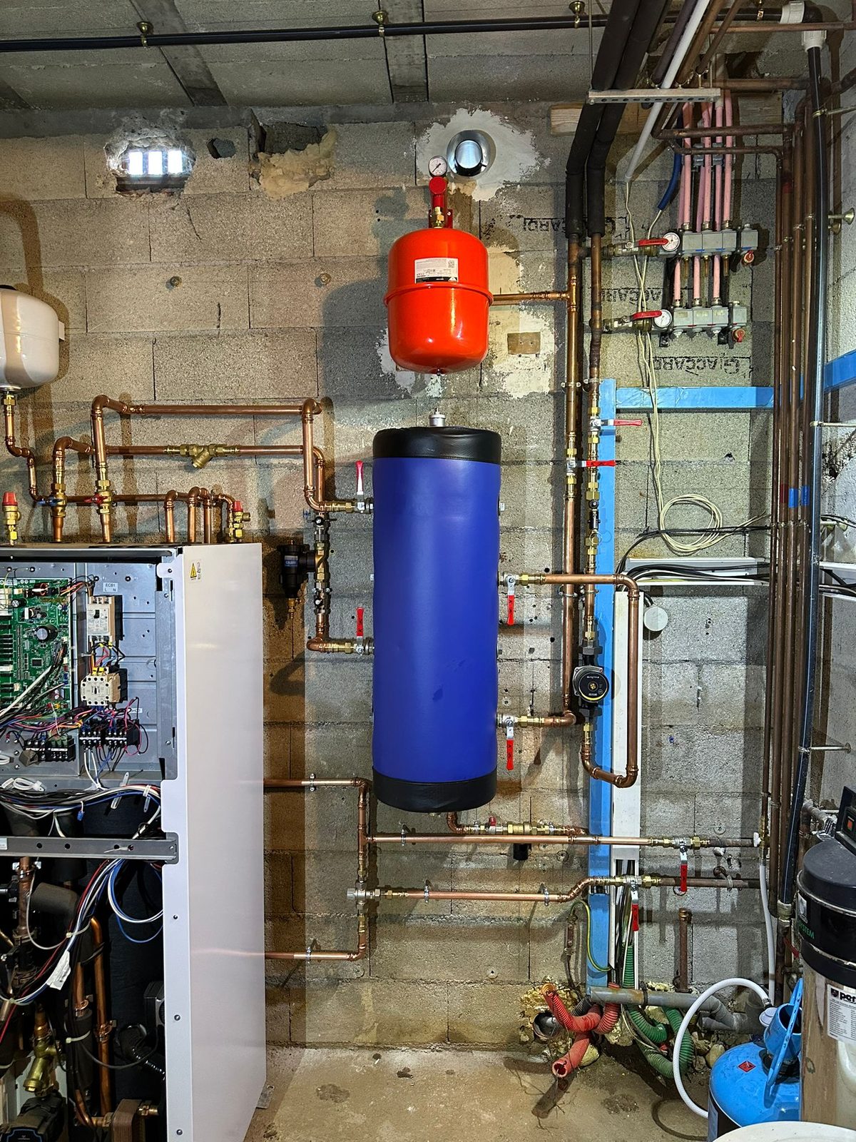 Raccordement hydraulique d'une pompe à chaleur air-eau : ballon de découplage, vase d'expansion, pot à boues, circulateur et collecteur de distribution en cuivre — installation MSC Climatisation dans le Var.