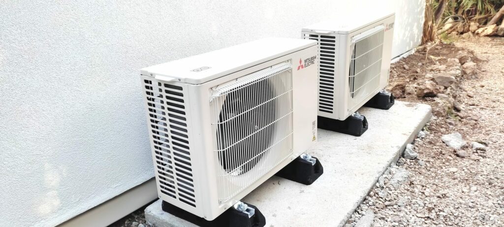 Deux groupes extérieurs Mitsubishi Electric posés sur supports au sol, alignés le long de la maison – MSC Climatisation