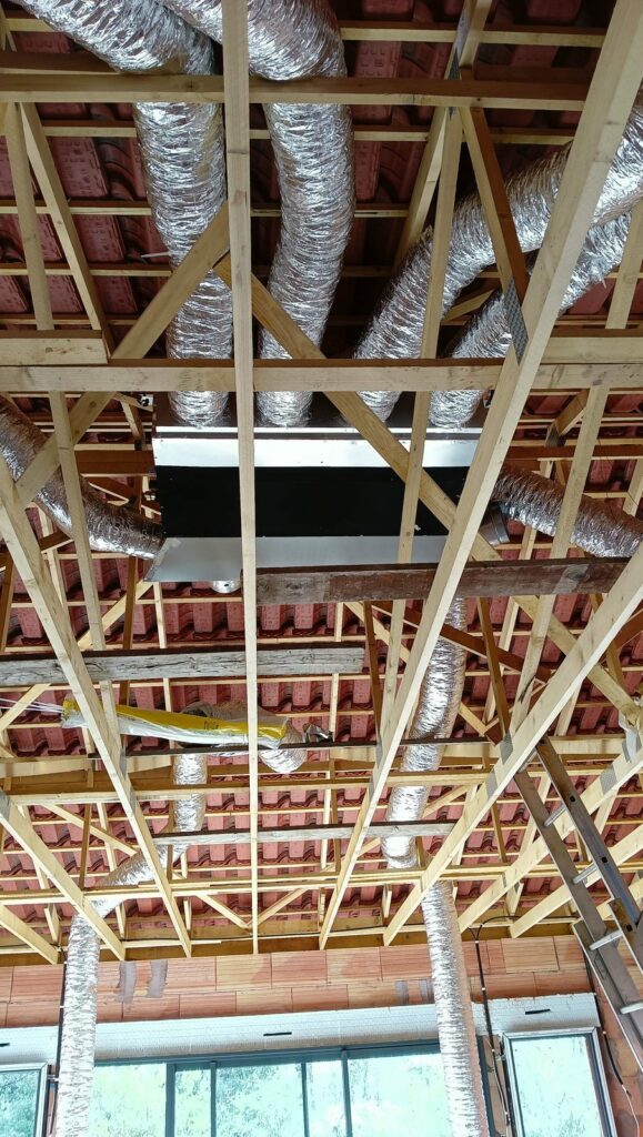 Gaines de soufflage souples posées dans la charpente d'une construction neuve, vers l'unité gainable suspendue – MSC Climatisation