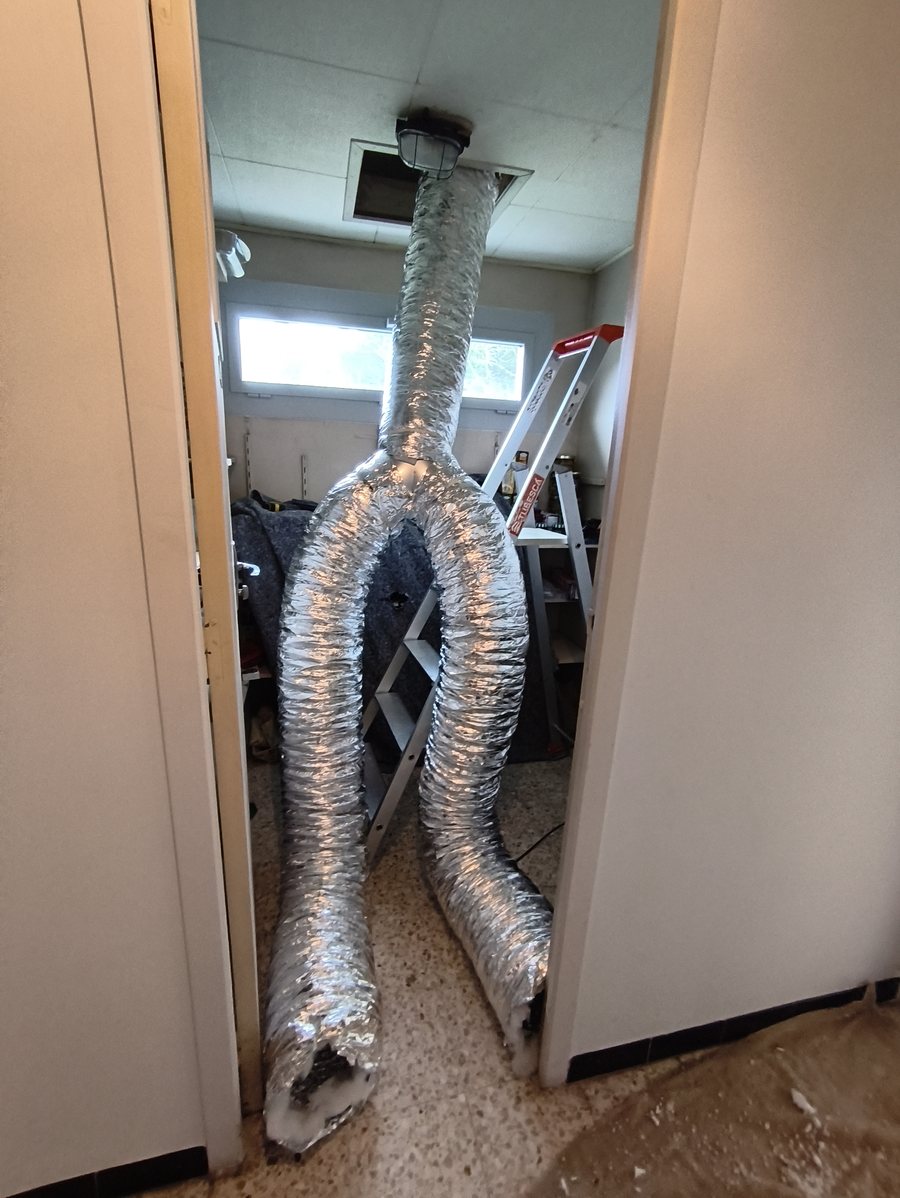 Gaines souples isolées passées par la trappe des combles pendant l'installation d'une climatisation gainable
