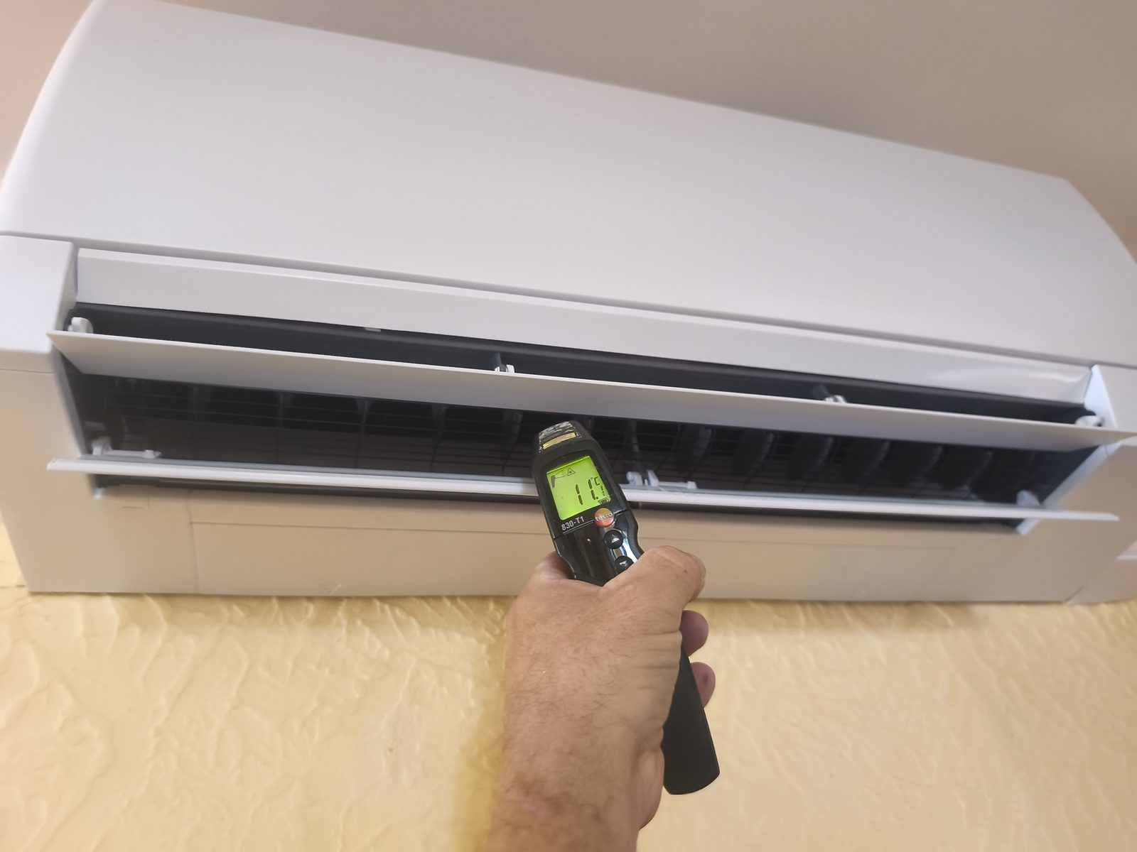 Thermomètre infrarouge visant la sortie d'air d'une unité murale ouverte — MSC Climatisation