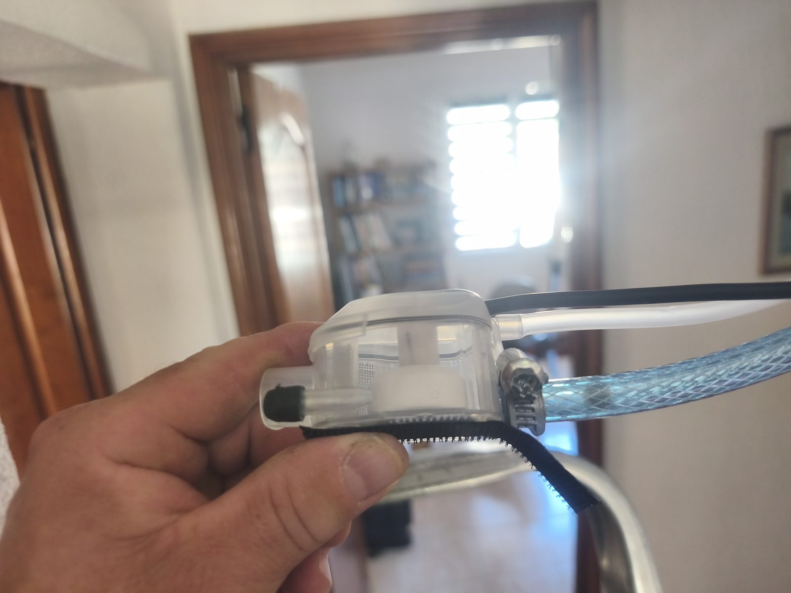 Main tenant une petite pompe de relevage de condensats raccordée à son tuyau — MSC Climatisation