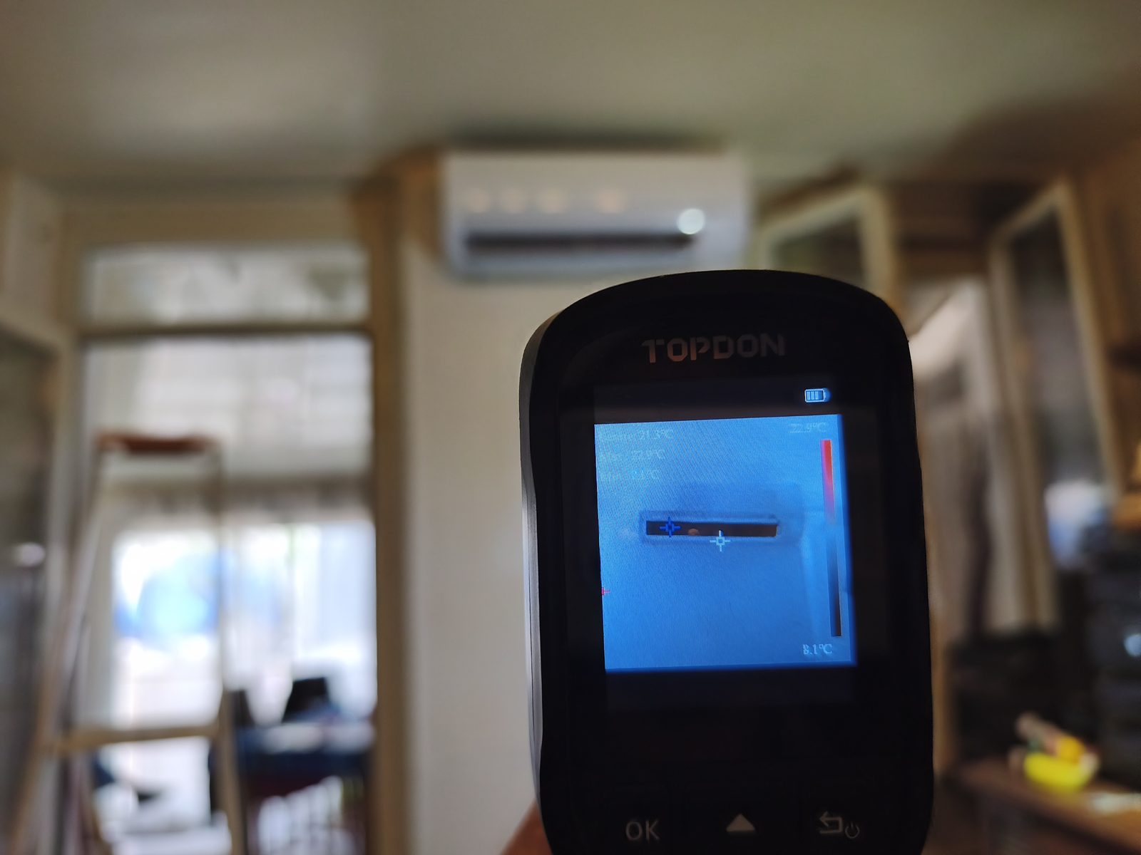 Caméra thermique au premier plan montrant l'air froid à la sortie d'une unité murale de climatisation visible au fond de la pièce — MSC Climatisation
