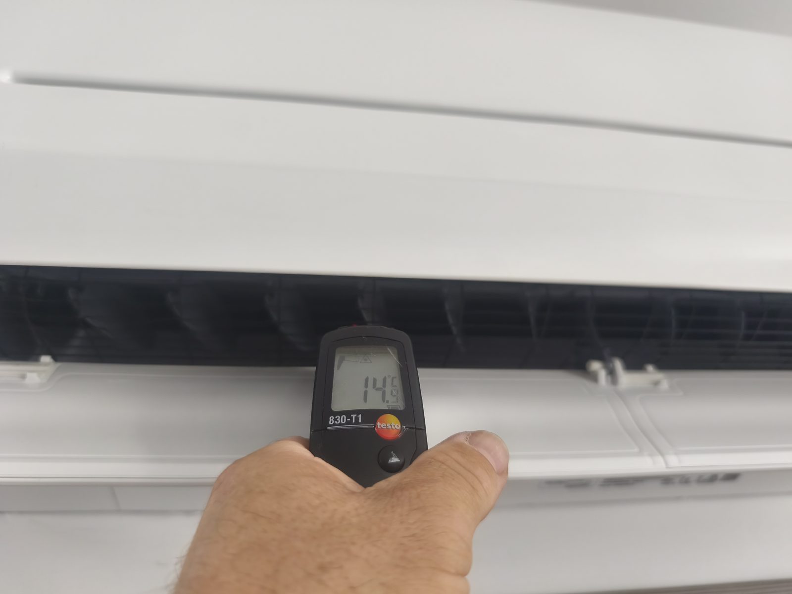 Thermomètre infrarouge devant la sortie d'air d'une unité murale de climatisation, affichant 14,5 °C — MSC Climatisation