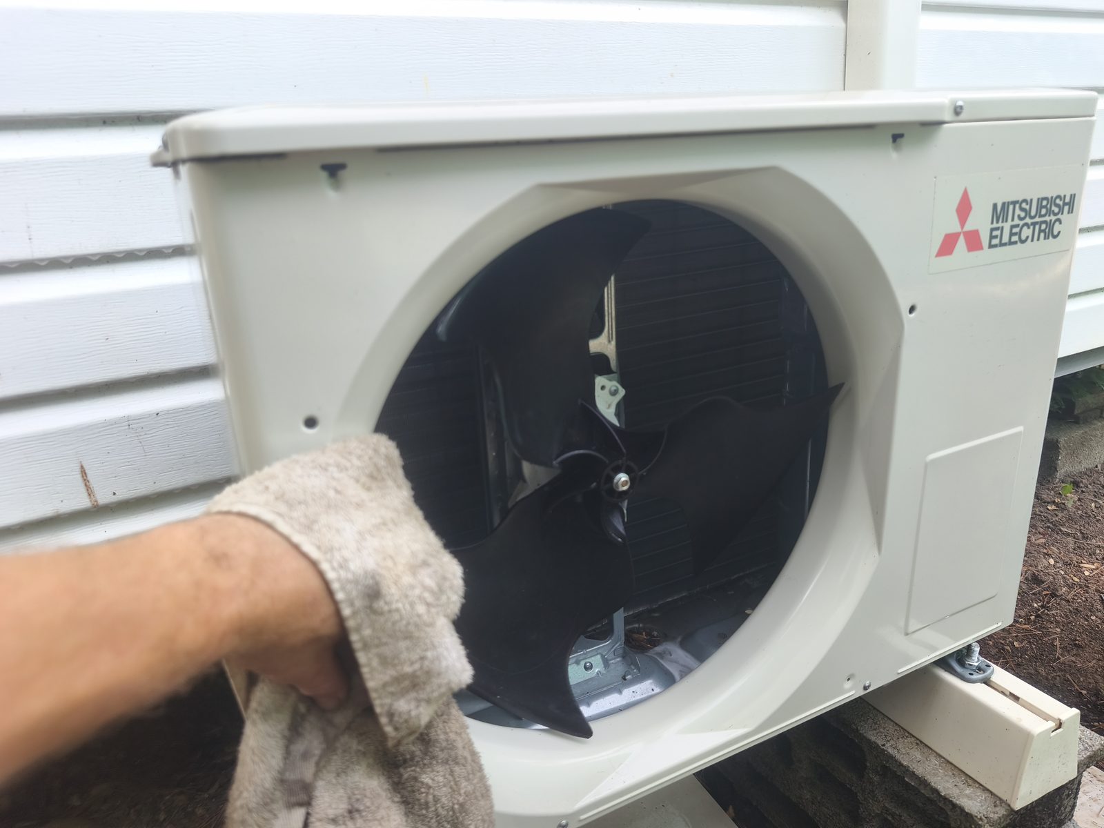 Hélice d'un groupe extérieur de climatisation Mitsubishi Electric nettoyée à la main, grille de protection retirée — MSC Climatisation